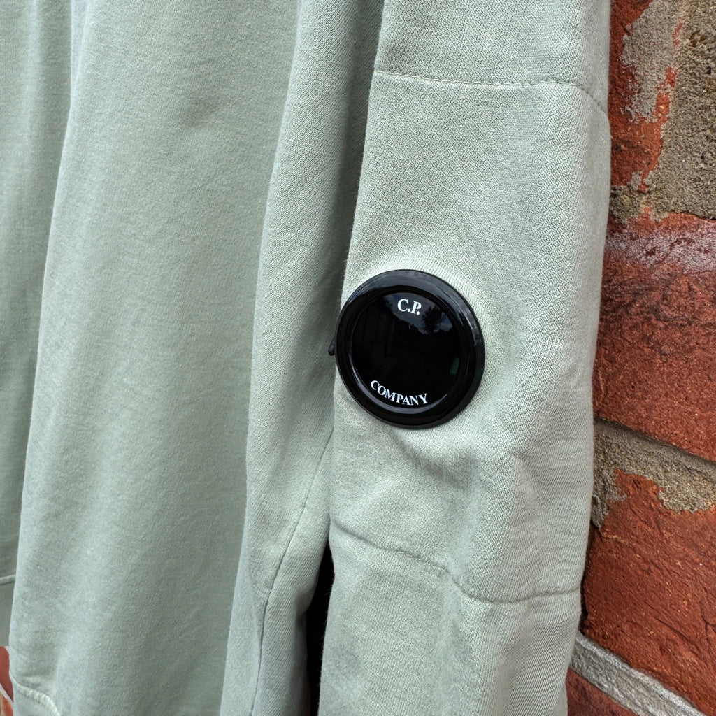 C.P. Company green sweatshirt with ribbed hem and signature goggle lens detail.