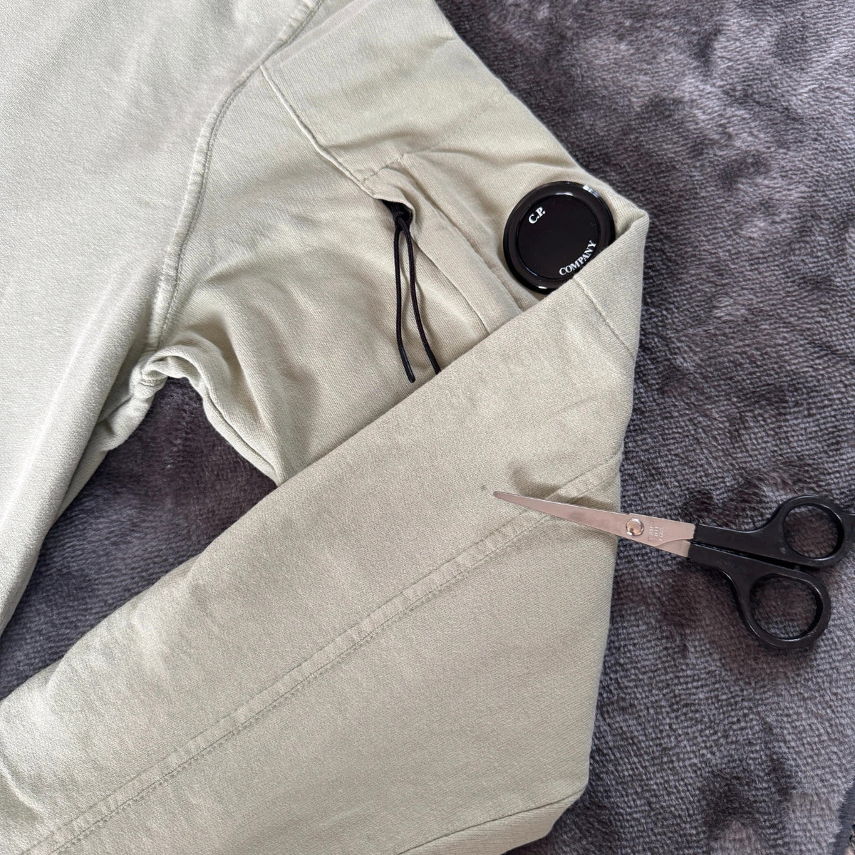 C.P. Company green sweatshirt with ribbed hem and signature goggle lens detail.