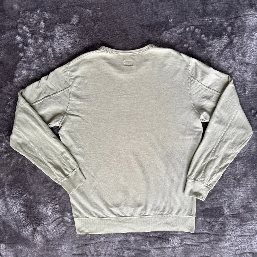 C.P. Company green sweatshirt with ribbed hem and signature goggle lens detail.