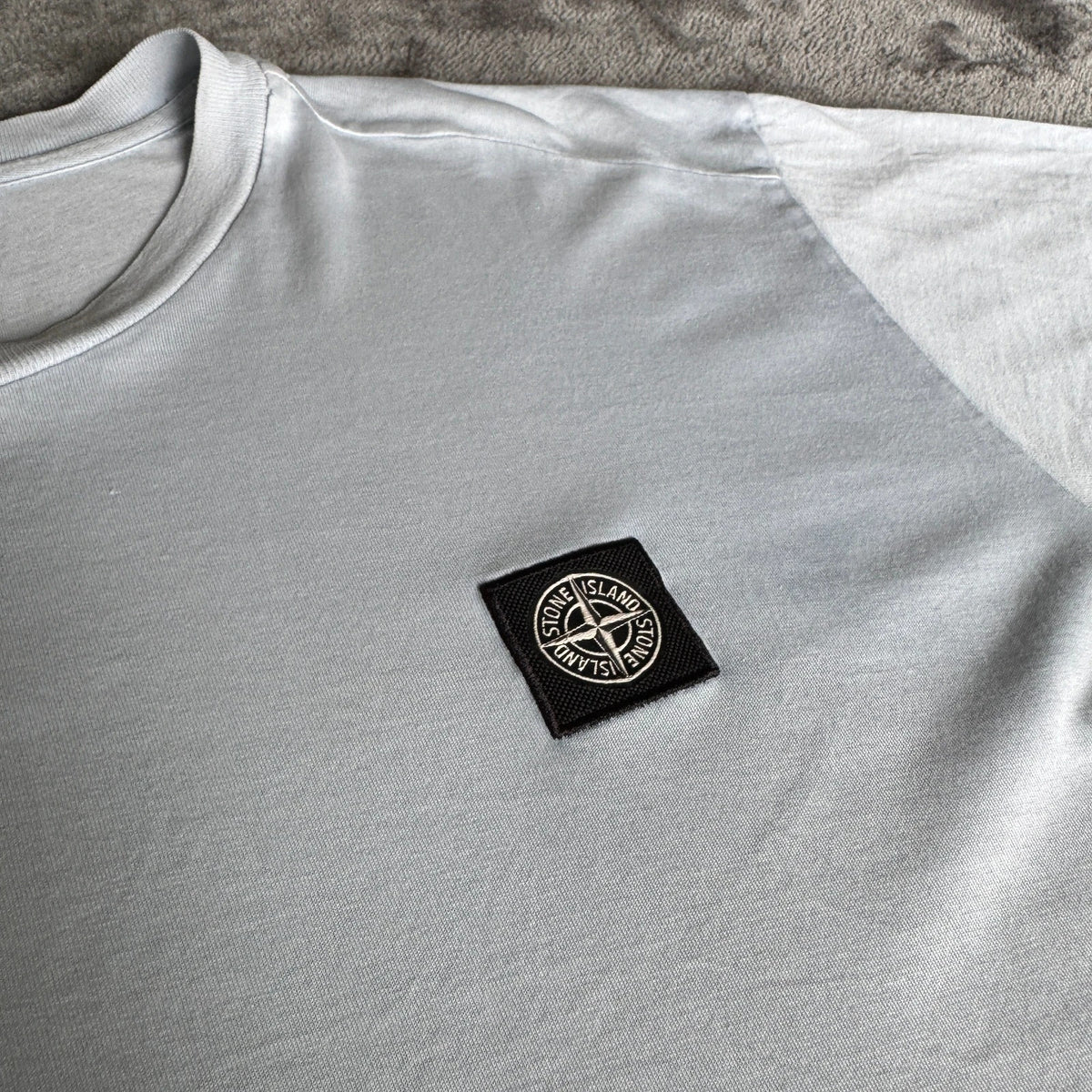 Stone Island light blue t-shirt with logo patch and crew neck design.