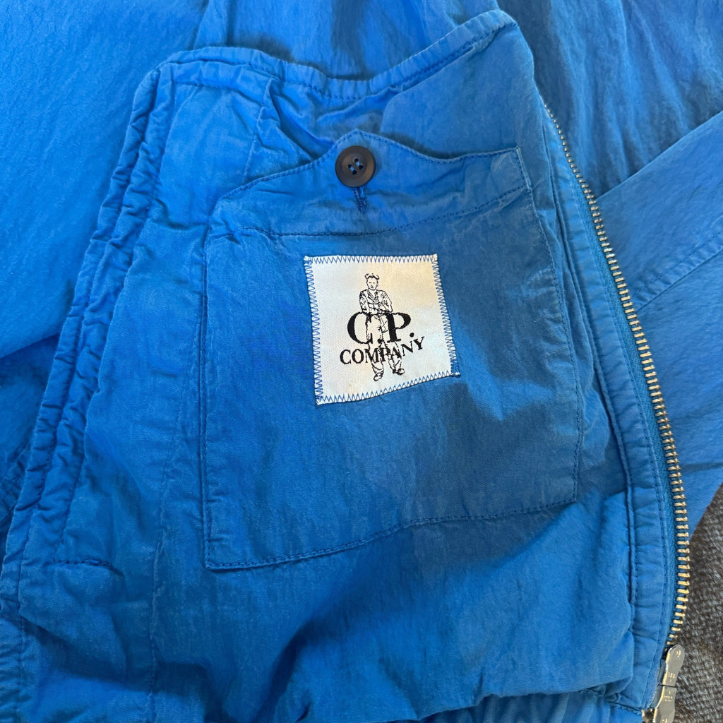 C.P. Company blue windbreaker jacket with big lens detail and garment-dyed finish.