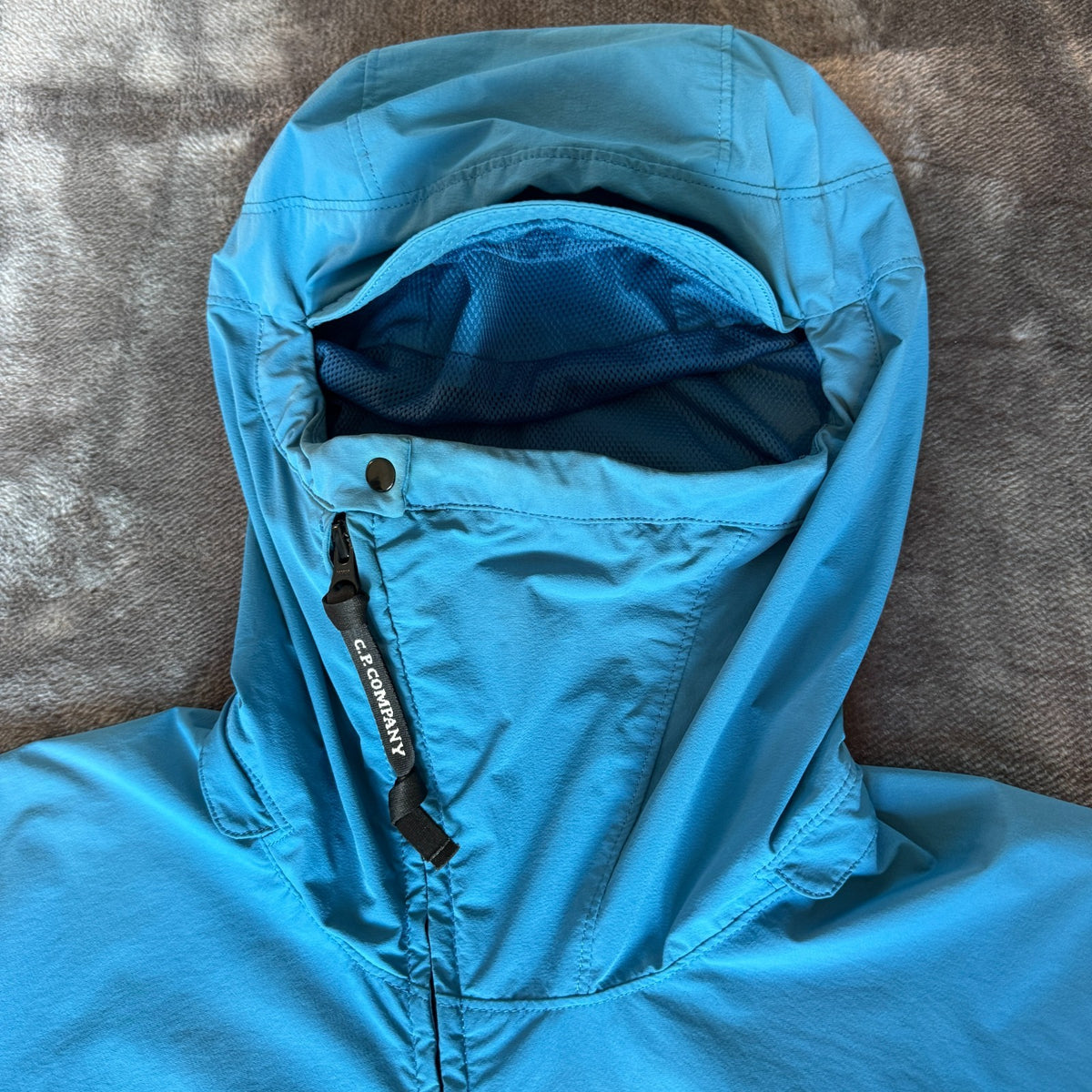 C.P. Company blue hooded smock with logo patch and Pro-Tek material details.