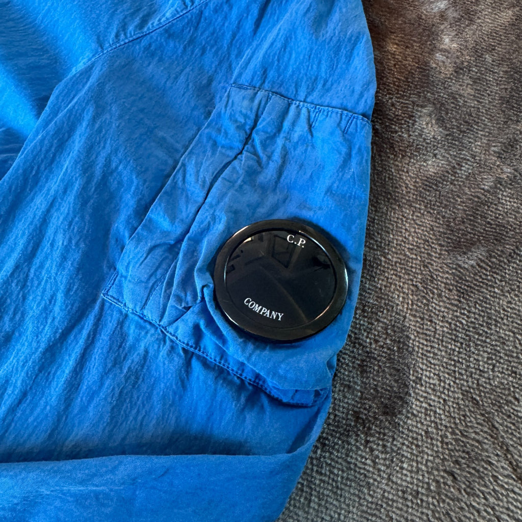 C.P. Company blue windbreaker jacket with big lens detail and garment-dyed finish.