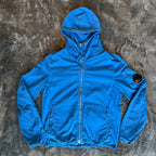 C.P. Company blue windbreaker jacket with big lens detail and garment-dyed finish.