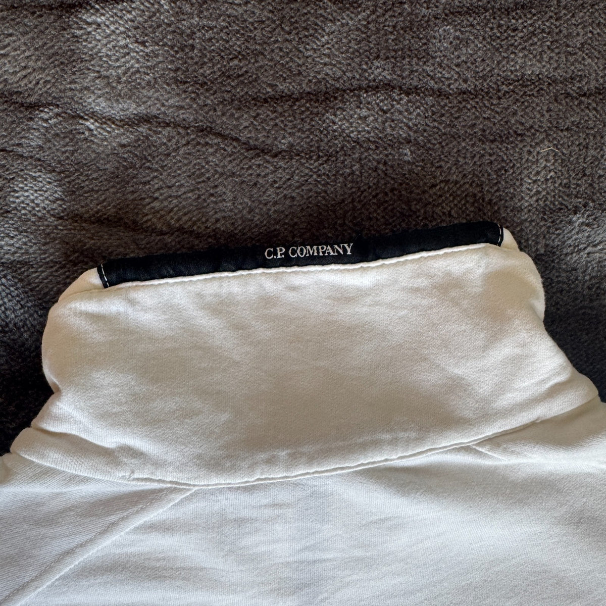 C.P. Company white quarter zip sweatshirt with logo patch and soft cotton material.