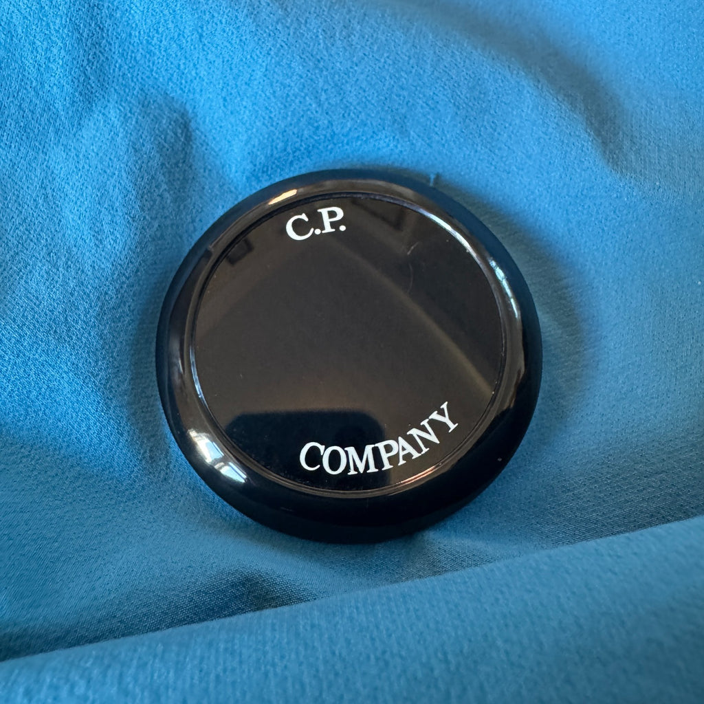 C.P. Company blue hooded smock with logo patch and Pro-Tek material details.