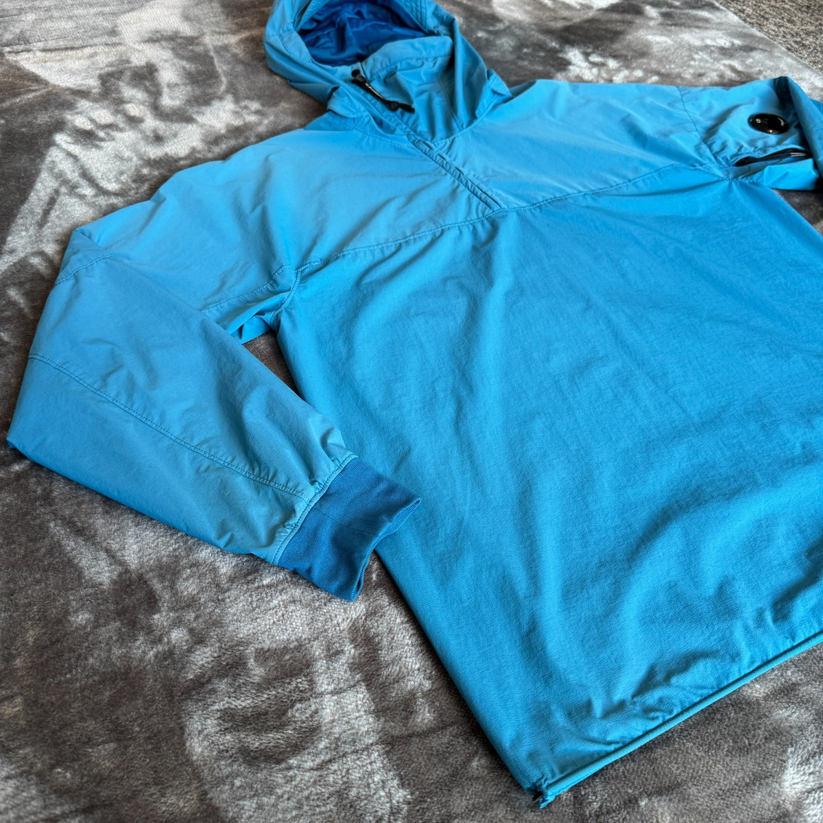 C.P. Company blue hooded smock with logo patch and Pro-Tek material details.