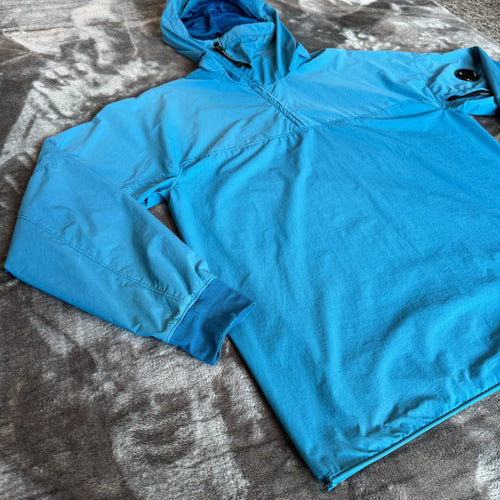 C.P. Company blue hooded smock with logo patch and Pro-Tek material details.