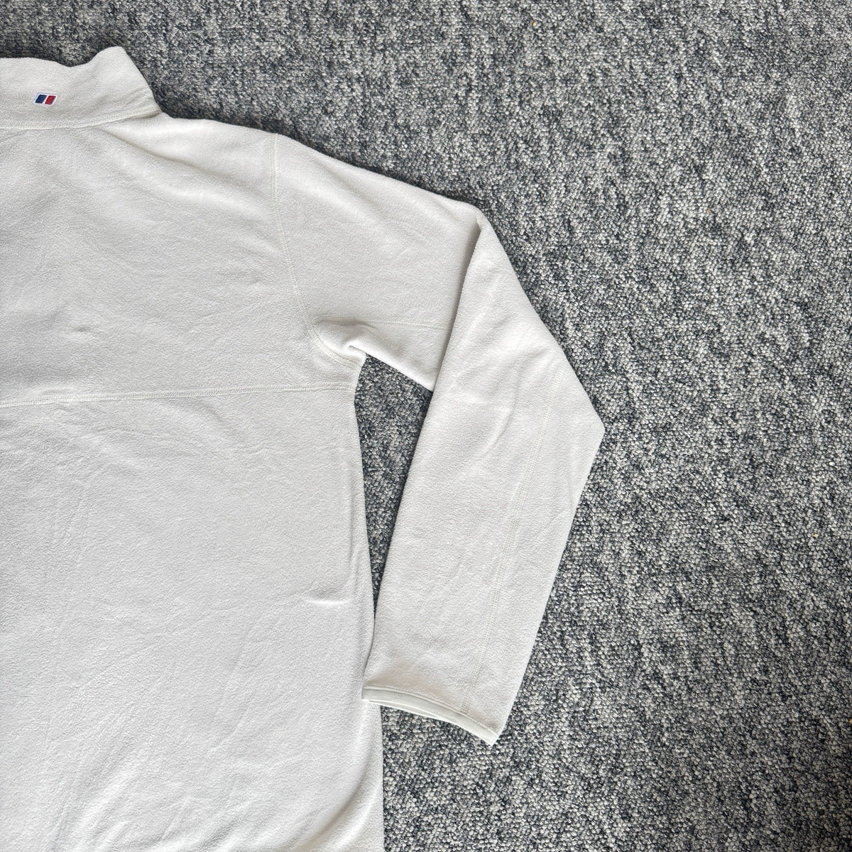 Berghaus off-white half-zip fleece with black logo pocket and stand-up collar.
