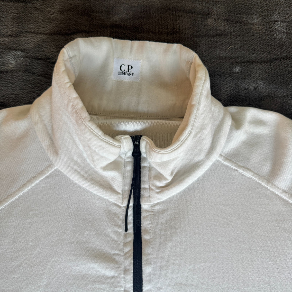 C.P. Company white quarter zip sweatshirt with logo patch and soft cotton material.
