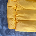 Stone Island yellow down jacket with crinkle reps texture and iconic compass logo.