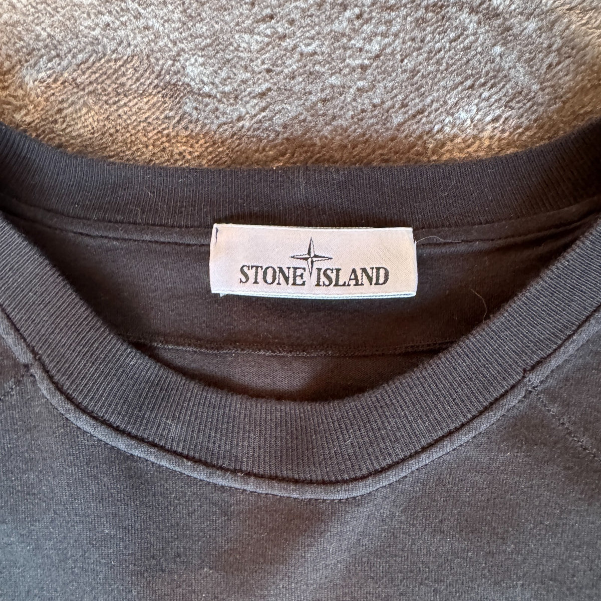 Stone Island black crewneck sweatshirt with 40th anniversary badge and logo patch.