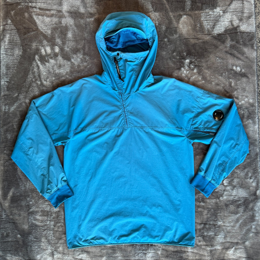 C.P. Company blue hooded smock with logo patch and Pro-Tek material details.