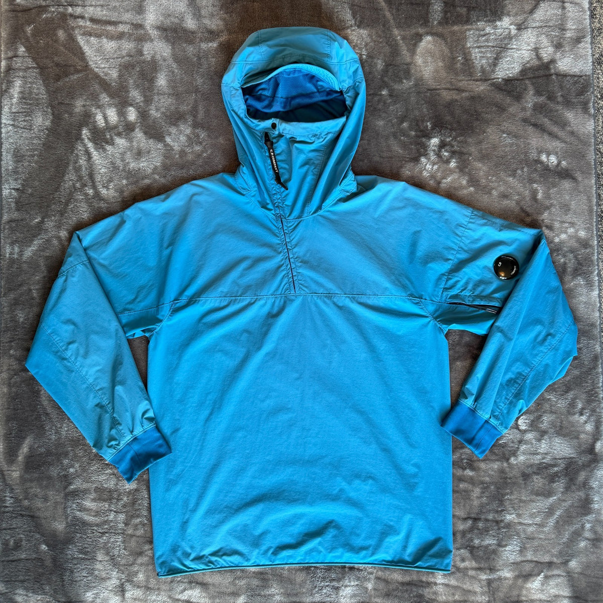 C.P. Company blue hooded smock with logo patch and Pro-Tek material details.