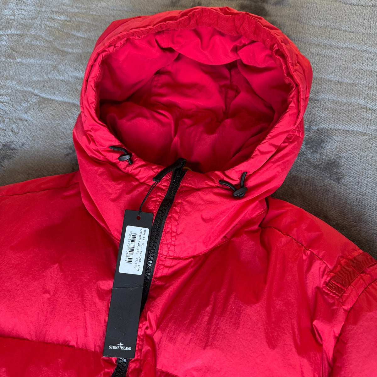 Stone Island red puffer jacket with compass patch, adjustable hood, and multiple pockets.
