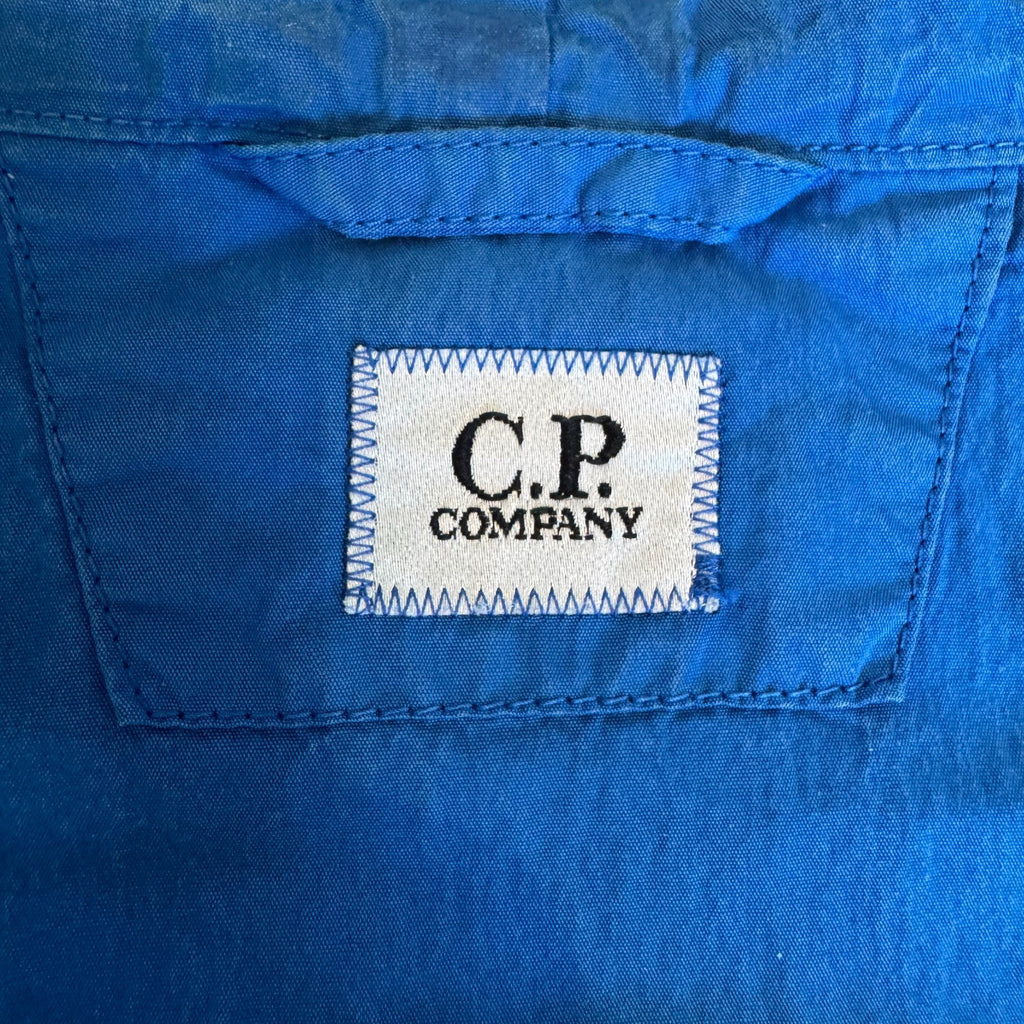 C.P. Company blue windbreaker jacket with big lens detail and garment-dyed finish.